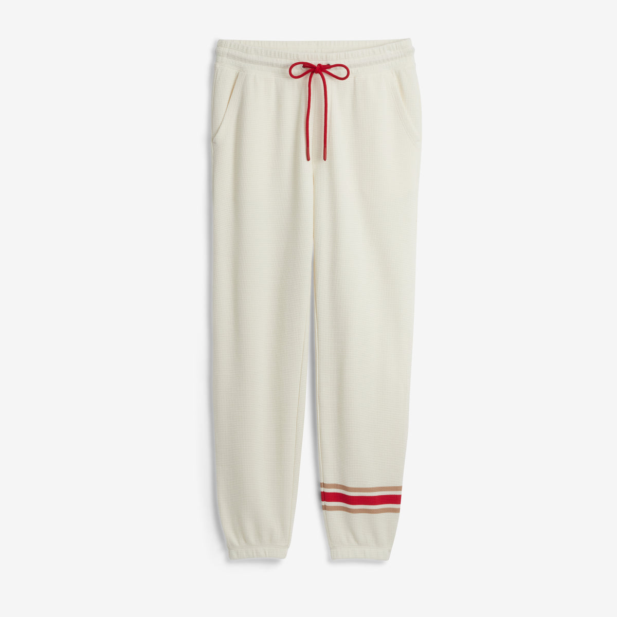 Cream-colored jogger sweatpants with a red drawstring and red and beige stripes near the cuffs, shown against a light gray background.