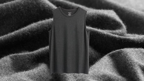 A dark grey muscle tank overlayed on a close-up photo of the same dark grey fabric. 