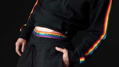 Cropped image of a model's midsection wearing black rainbow hoodie, sweatpants, and underwear. 