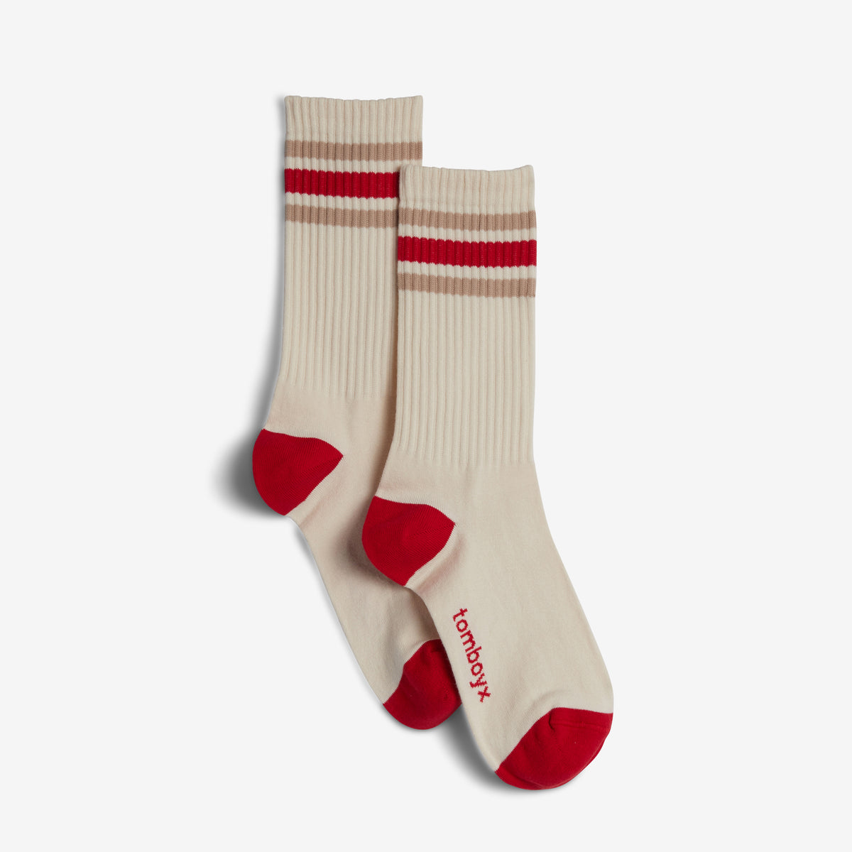 A pair of cream ribbed crew socks with red toes and heels, featuring two horizontal stripes near the cuff (one red, one beige), with the brand name 'tomboyx' printed in red on the side.